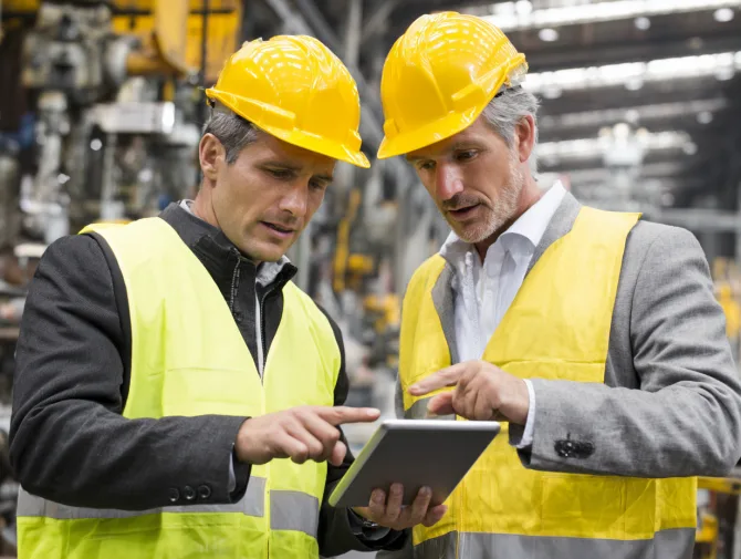 Acoustic consultant reviewing noise assessment results with factory manager on tablet