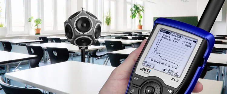Sound level meter on tripod conducting acoustic measurements in auditorium
